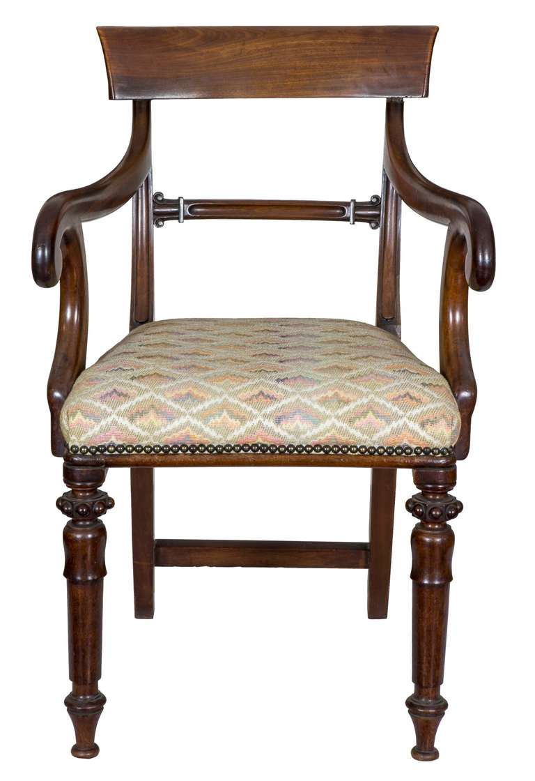 This armchair, composed of heavy figured mahogany, immediately distinguishes itself with strongly developed scrolled arms which are reinforced stylistically with its immediate support structures, which successfully complete the line and form of the