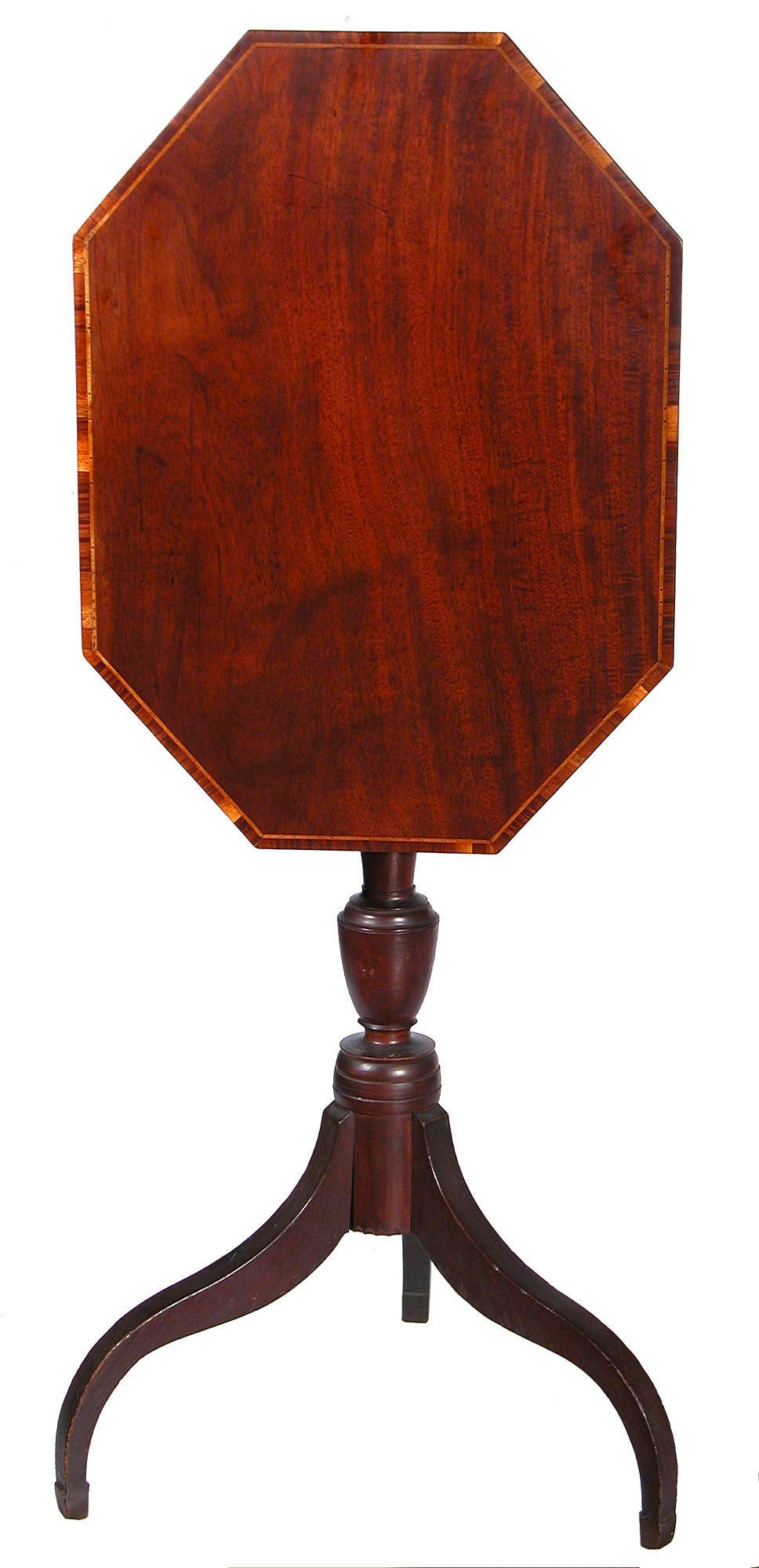 This tilt-top table has a solid top of figured mahogany. Of most interest is the fine inlaid banding around the top. Note the multicolored inlay strip which is bordered by a variegated banding, which is composed of a multitude of contrasting woods