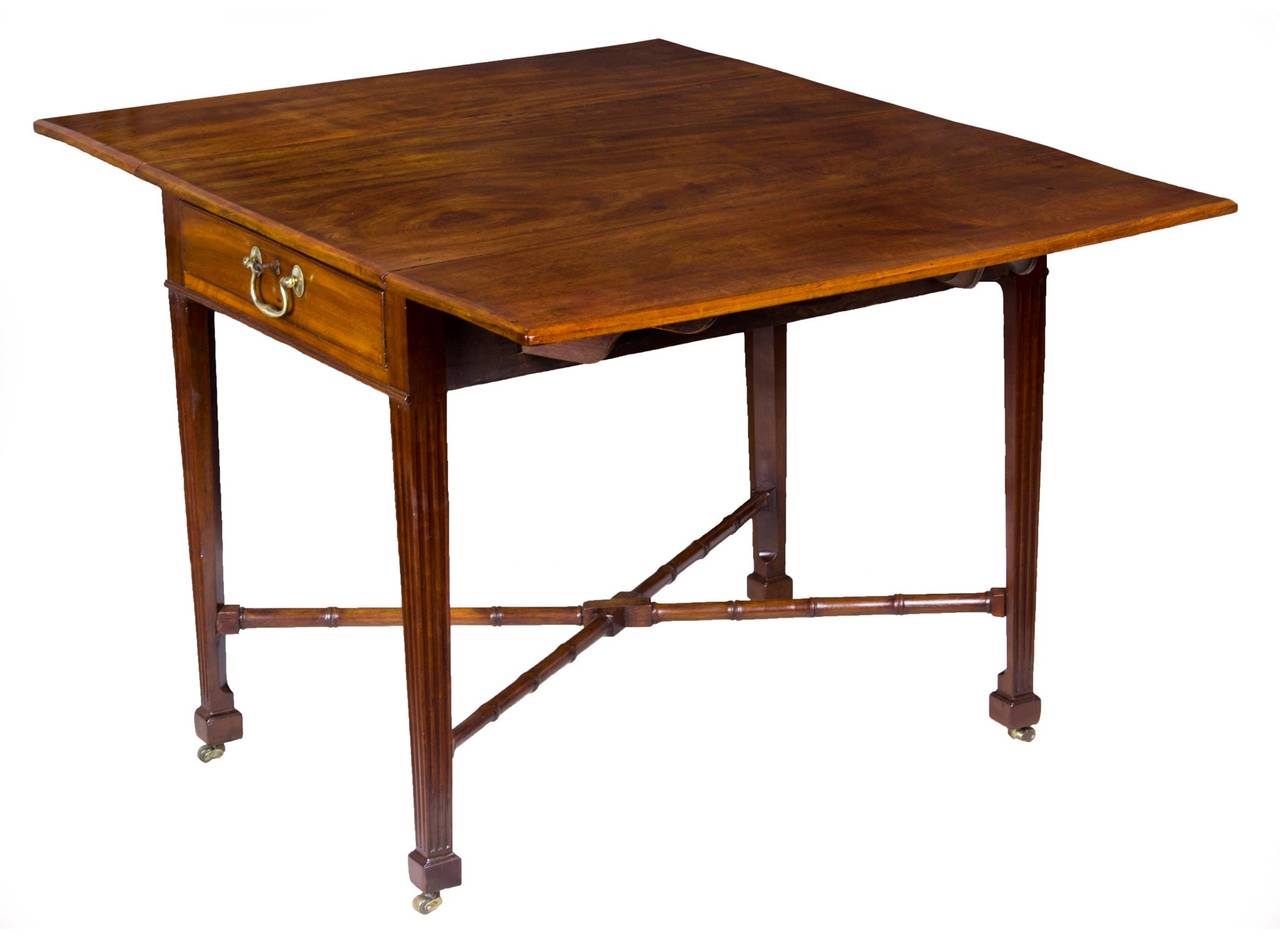 This Pembroke table is composed of beautifully figured mahogany single board slabs which have, over time, developed a beautiful patina and depth. The legs are reeded and chamfered in the back just above the square Marlborough foot. The drawer has