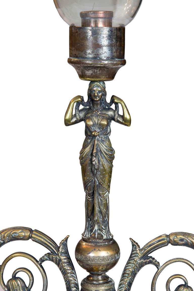 This is a pair of highly decorative lighting candelabrum with what appears to be their original glasses. It is rare to find these fixtures with three lights, as developed as these are, with their figural motifs. 

Originally, these were silver