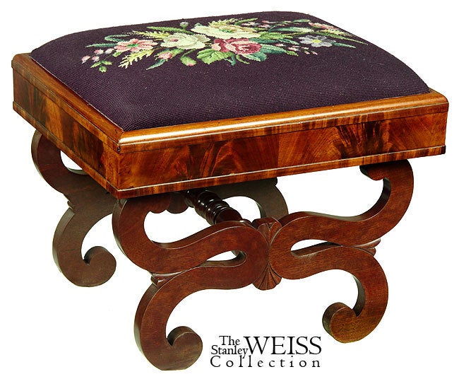These footstools employ the Curule leg design used throughout this period. A related footstool labeled by Hancock, Holden, and Adams is illustrated in the magazine Antiques, May 1976 (see below). 

A comparison with the related footstool shows the