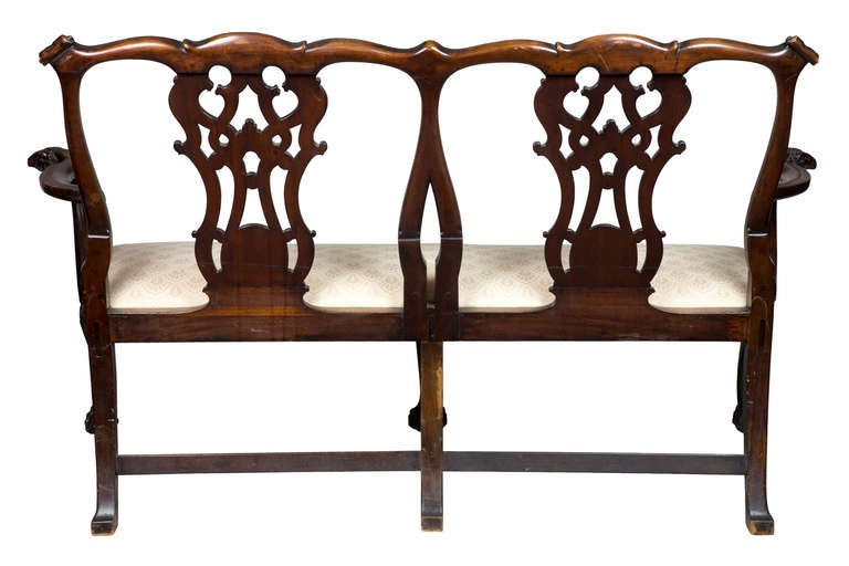 This settee is a tour de force of carved elements which make a most commanding presentation. The Chippendale style here is embellished with, 1) fully carved backsplats, 2) scrolled crest rail corners, 3) arms with fabulous, rarely seen, ram’s heads,
