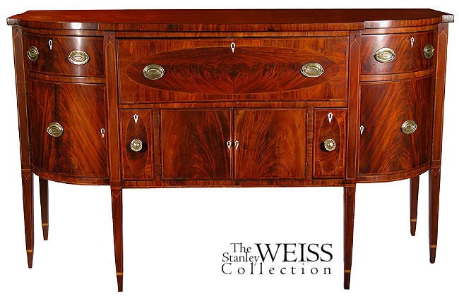 This sideboard is finely constructed with highly figured mahogany and line inlays of satinwood and ebony. It has everything one would expect in a sideboard including bottle drawers and the largest writing desk we have seen in a sideboard. Of note is