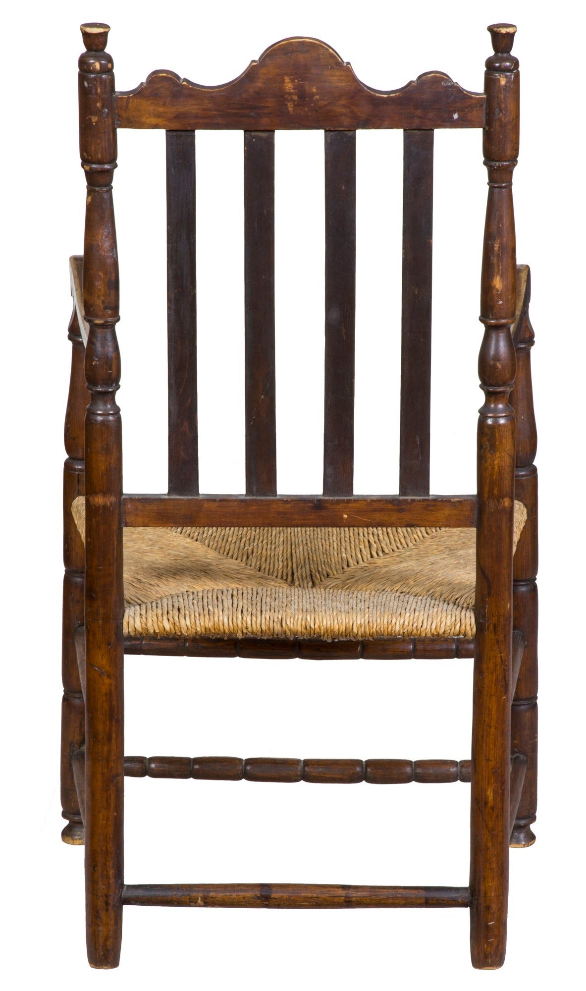 This armchair relates to an example shown in Bishop, the American chair: Three centuries of style (see scan) with reeded vertical slats on the back and the sausage turnings at the base. Unlike the comparative example illustrated, the crest of our