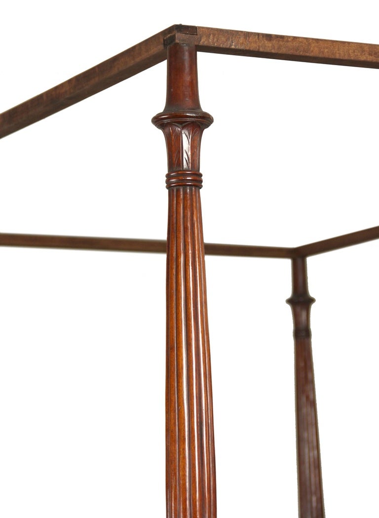 This is one of the finest Classical beds we've handled. Not only are the front posts magnificently carved with details above and below an expanse of deep reeding, but, all four posts are also carved. If this weren't enough, the headboard is carved