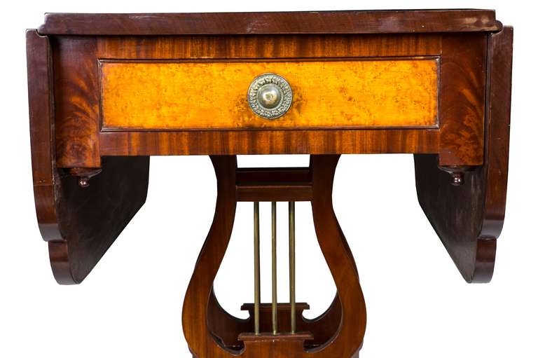 This is a wonderful small drop-leaf table with open lyres, supported by saber legs, which provide a very open, airy feeling, making it comfortable to use, as there are no straight legs to interfere. This table has been realigned from its base at 90º