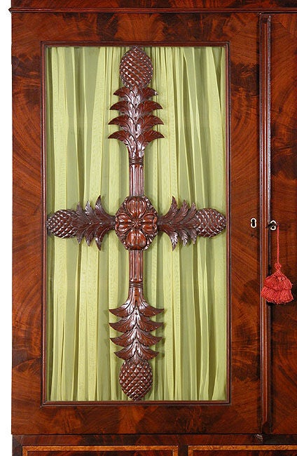 This bookcase on stand is highly distinctive and relates to a school of cabinetry in Baltimore attributed to Anthony H. Jenkins. The notable element is the pair of magnificently carved door panels with medallions and water leaves. Another