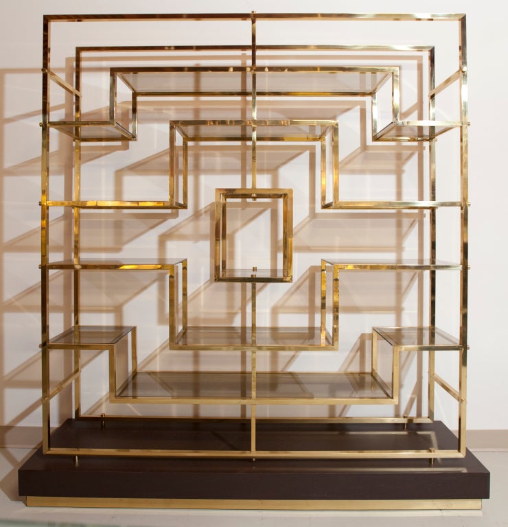 Brass etagere in geometrical design with smoked glass shelves. Pedestal in dark brown lacquer with brass base rail.