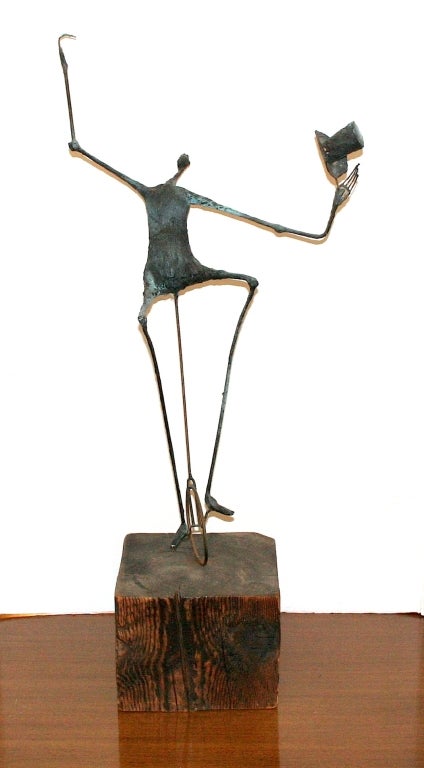 Modernist sculpture of a wire figure man on a unicycle resting on a wooden base.