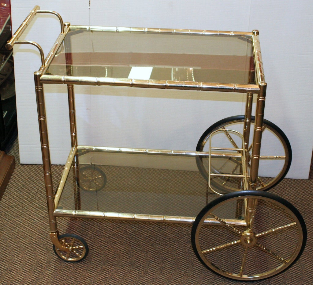1960's faux bamboo brass rolling bar cart with two tier smoked glass shelves. Lower tier has 3 spots for your liquor bottles.  Measurements does not include handle.
