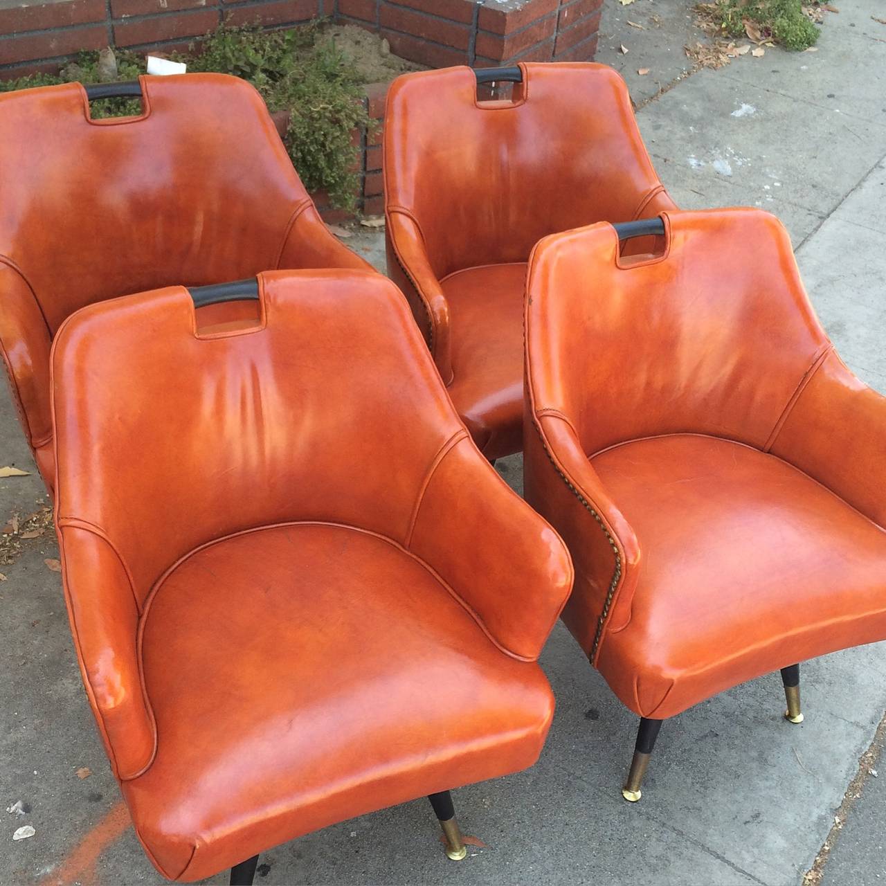 Four leather games chairs. Unique smaller base and legs carry the four orange game table chairs with wooden pull at top very nice and comfy.