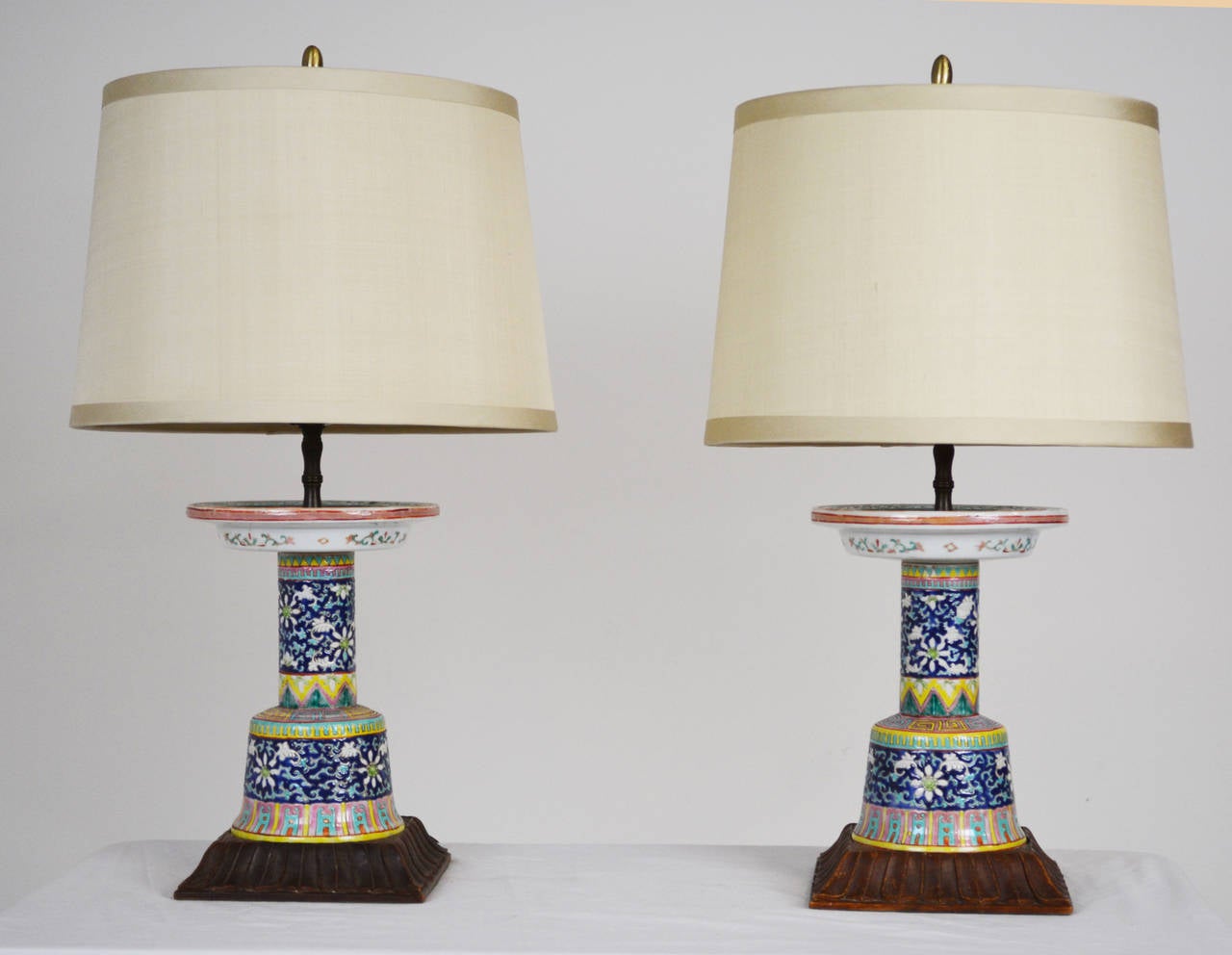 A lovely pair of lamps made from Chinese porcelain candlesticks on carved wooden bases. Shades not included, for display only.