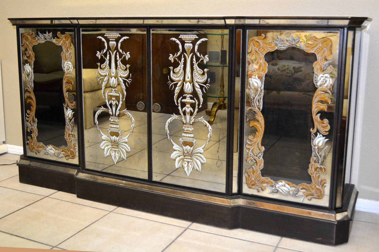 An exceptional mirrored buffet with built-in bar in eglomise mirror and glass. Two central doors open to reveal storage, with two side doors with central clear glass surrounded by eglomise decoration open to reveal a backlit bottom panel that