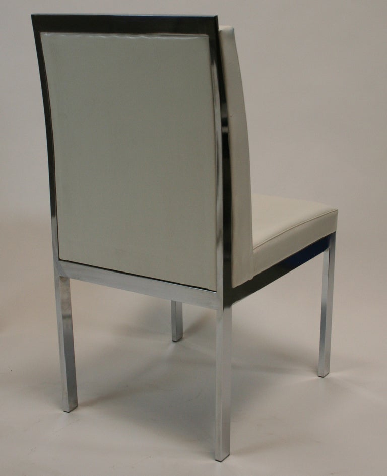 Very sculptural side chairs by Design Institute of America. Chromed flat bar stock  forms legs, tapering gracefully into back support. In original white vinyl. 4 additional chairs available.