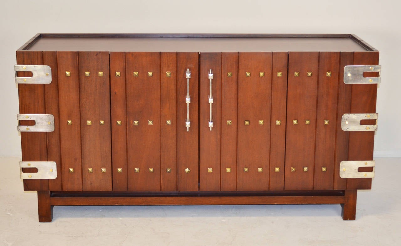 A truly rare cabinet / buffet by Edmond J. Spence for Industria Mueblera with a pair of bi-fold doors concealing four drawers on the left and a single shelf on the right. The cabinet is mounted with hand made metal strap hinges, pyramidal bosses and