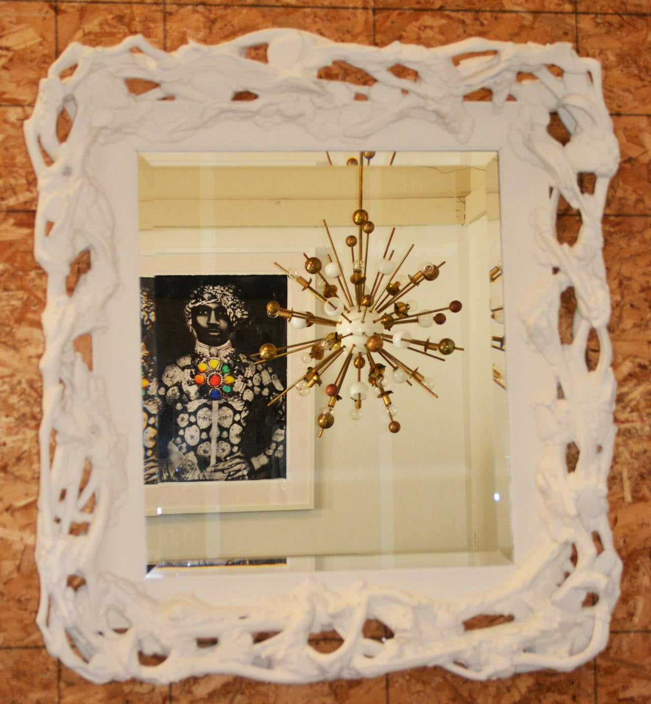 A unique mirror with beveled glass plate surrounded by a resin frame in the form of tree roots entwined around stones.