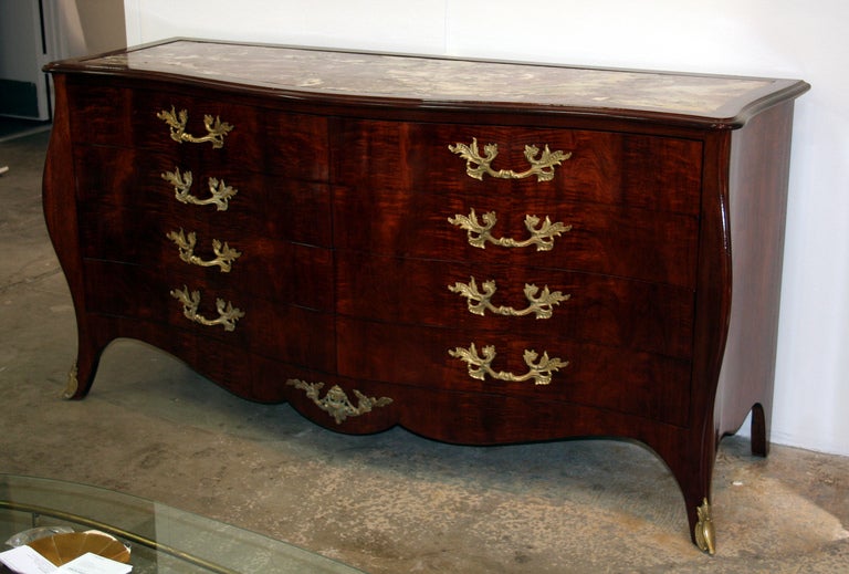 Magnificent mid-century modern 8 drawer dresser with bombe front and corners with gilt bronze mounts. Beautiful flame mahogany veneers and inset marble top. The best of Hollywood Regency and Maison Jansen style.