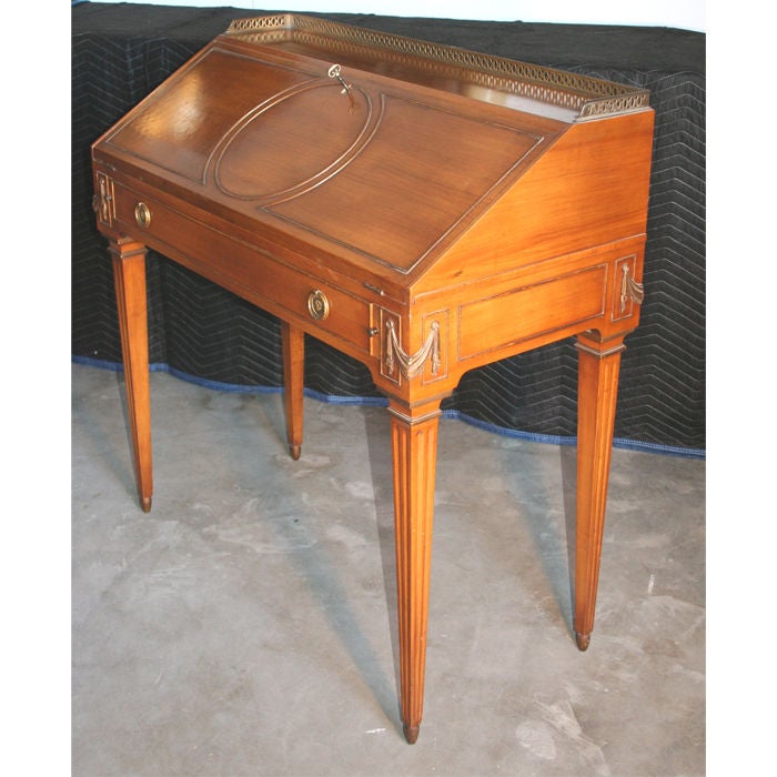 A chic little slant top lady's writing desk in the style of Maison Jansen. Fruitwood with gilt accents and pierced brass gallery. Lovely size and exceptional quality. Missing key, but not an issue