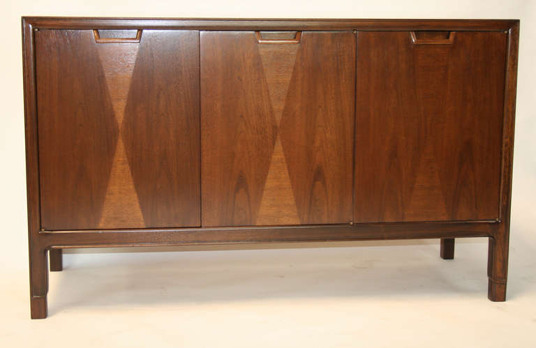 An elegant pair of three door cabinets with unique carved legs. Doors have 