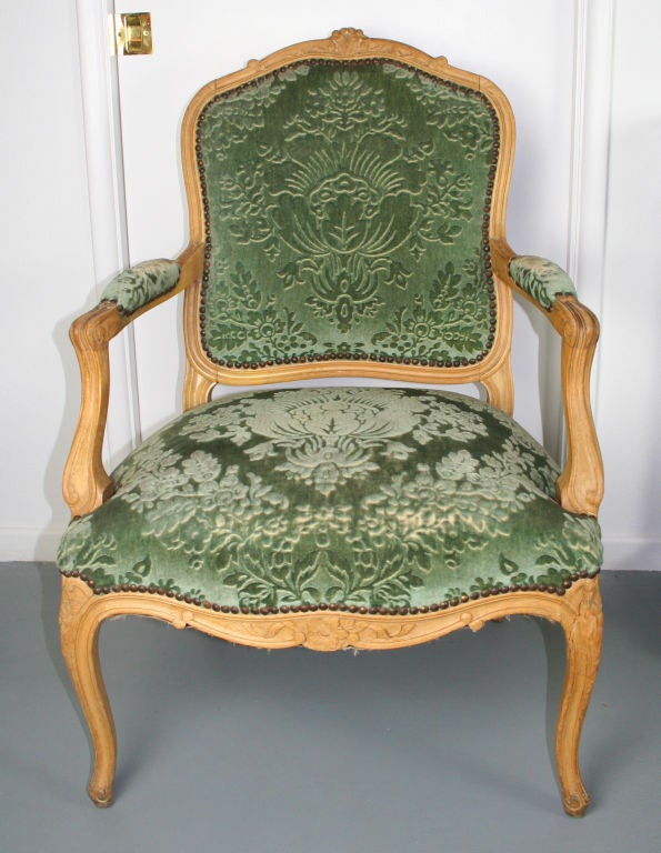 A pair of Louis XV style fauteuils, circa 1900, with lovely floral carving. Original gaufrage velvet upholstery, with some wear to upholstery on arms.