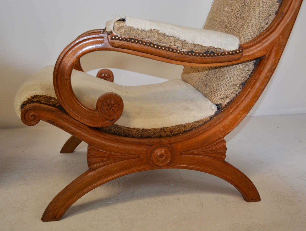 An outstanding pair of Campeche chairs of light fruitwood with carved decoration. The lateral non-folding curule base connecting with a rosette at the juncture of the base and back support. With original horse hair stuffing, ready for upholstery.