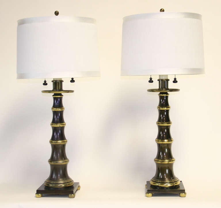 Very chic pair of dark bronze faux bamboo lamps with brass accents. Asian inspired with lovely detailing. Double sockets with original decorative pulls. 32" to top of socket cluster.