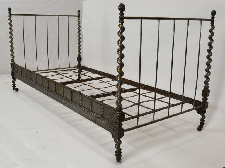 19th Century cast iron campaign bed with twisted corner posts and acorn finials on original wheels. Mattress not included.