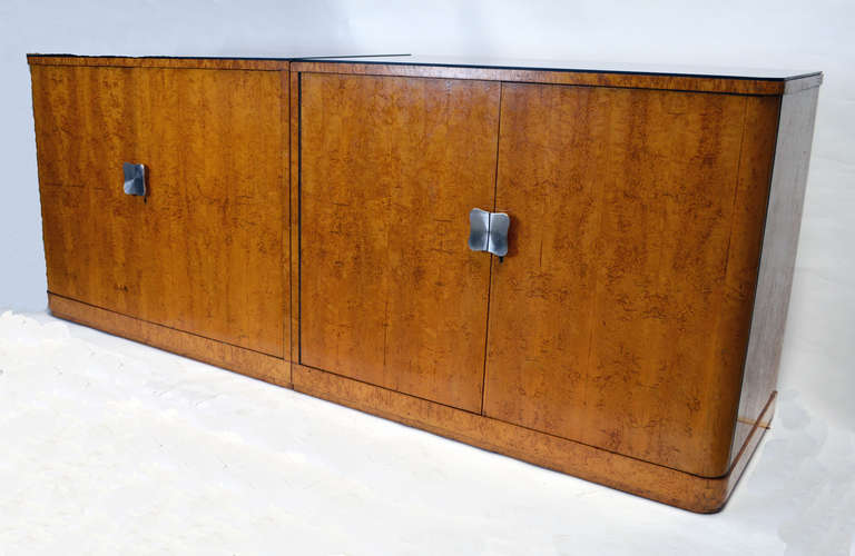 A large pair of bookmatched burl veneer cabinets that form a large buffet. Tops in original black glass. One cabinet with internal drawers on one side, and adjustable shelves in the other. European, most likely Austrian or Czech.