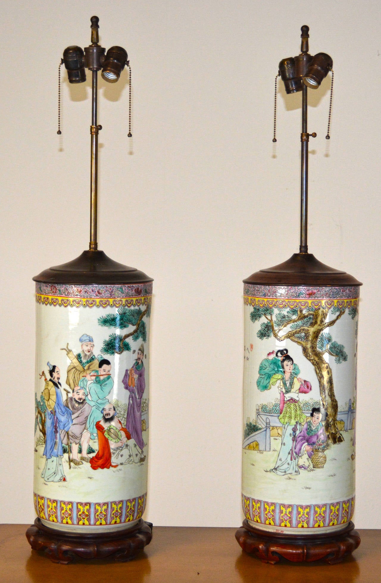 A lovely pair of vintage Chinese famille rose lamps with lovely scenes. These lamps are of a large-scale that is very impressive. Rewired with new double cluster sockets in patinated bronze. Height to top of porcelain is ___.