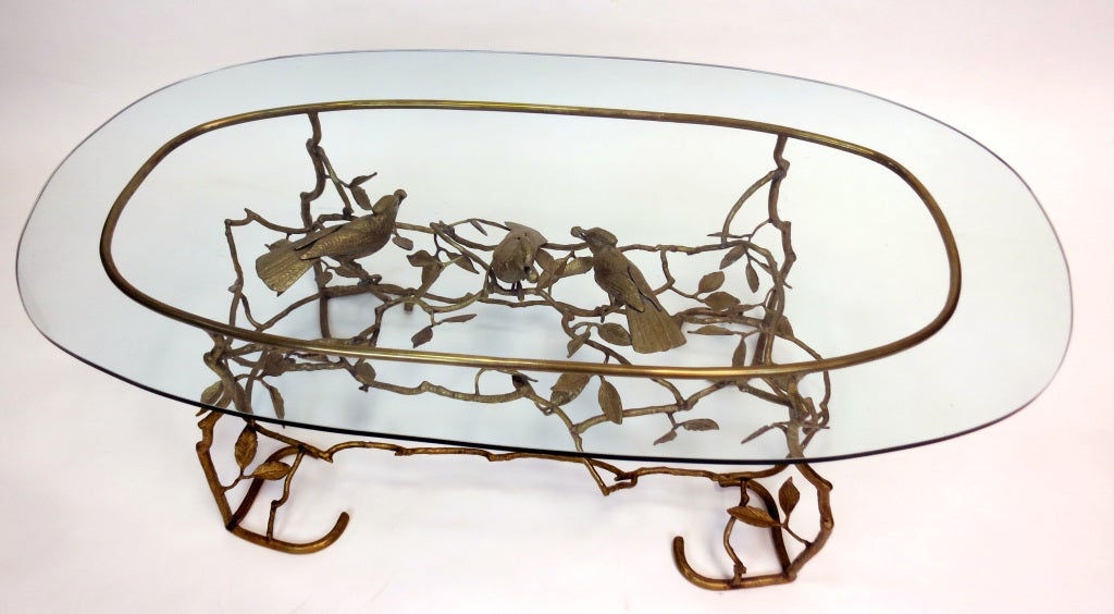 Sculptural brass coffee table with three birds in branches forming the base. Conforming oval glass top.Lovely form and excellent quality. Dimensions of base - 39"L x 17.5"W x 16"H