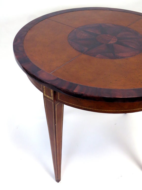 Table clad in leather with tooled gold detailing and inset faux tortoise top and edge. Abstracted French mid-century modern gueridon form. Great as a center, side or games table.