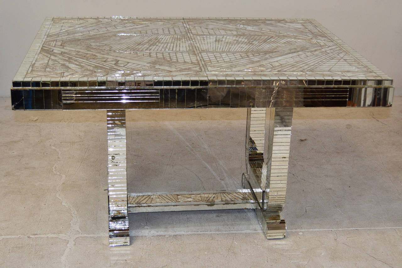 A stunning period art deco dining table completely covered in mirror tiles in the most amazing geometric patterns. A base comprised of two "U" shaped supports with a mirrored stretcher supports a mirrored top. The top is capable of