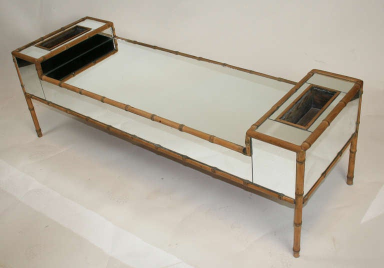 Chic coffee table covered in mirror and framed in faux bamboo trim. Upturned ends with planter pockets.