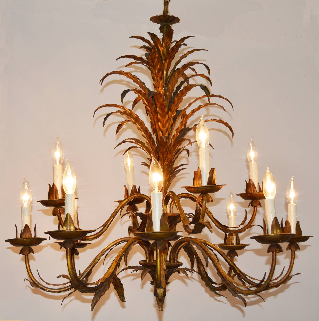 A stunning large twelve-light gilt metal chandelier composed of thin leaves in a palm style. The central support is adorned with out scrolled leaves emanating two tiers of scrolled arms with similar decoration. Rewired and ready to hang. 