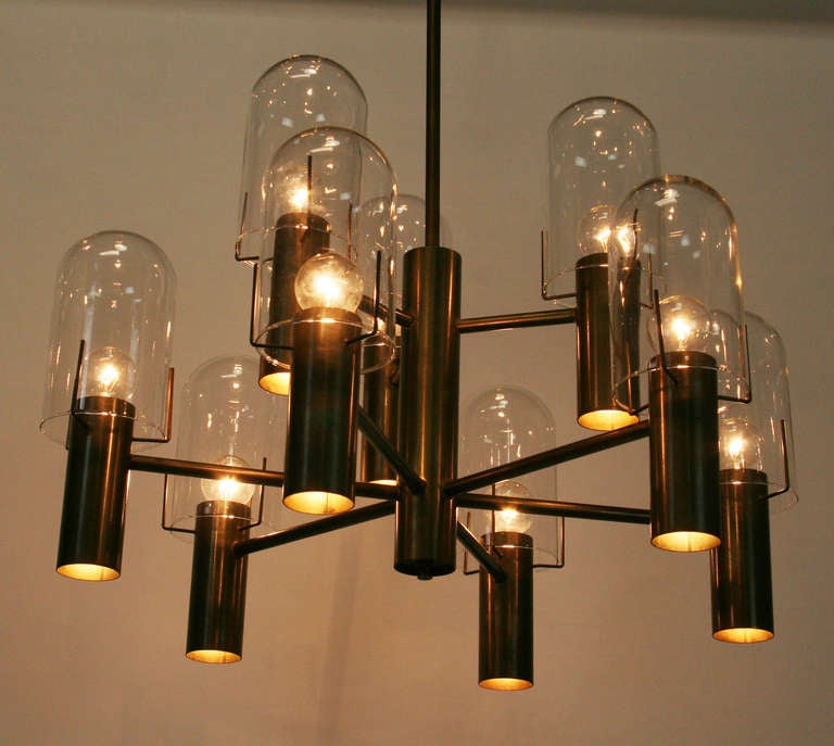 Bronze chandelier by Stuart Barnes for Robert Long with 9 arms. Each arm has a downlight and a bulb with glass hurricane.