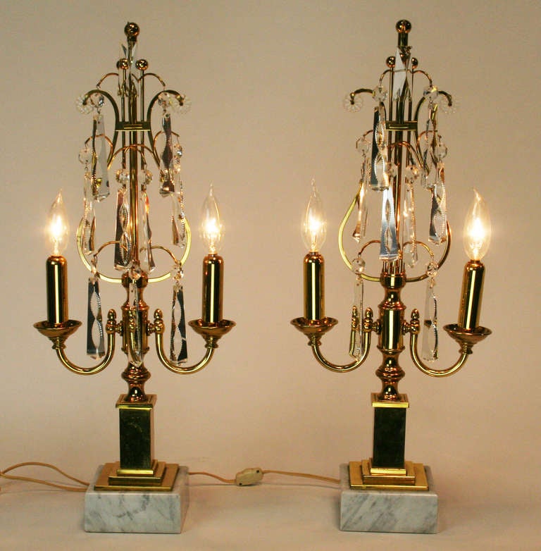 Nice pair of two light girandoles in brass on marble bases with cut crystal prisms. Interesting modern take on a classic form.