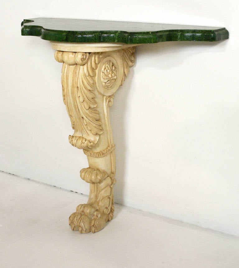 A painted, wall-mounted console table, with a single scrolling leg, deeply carved stylized leaf facing front, to hairy paw foot, 2'' thick faux marble shaped top.