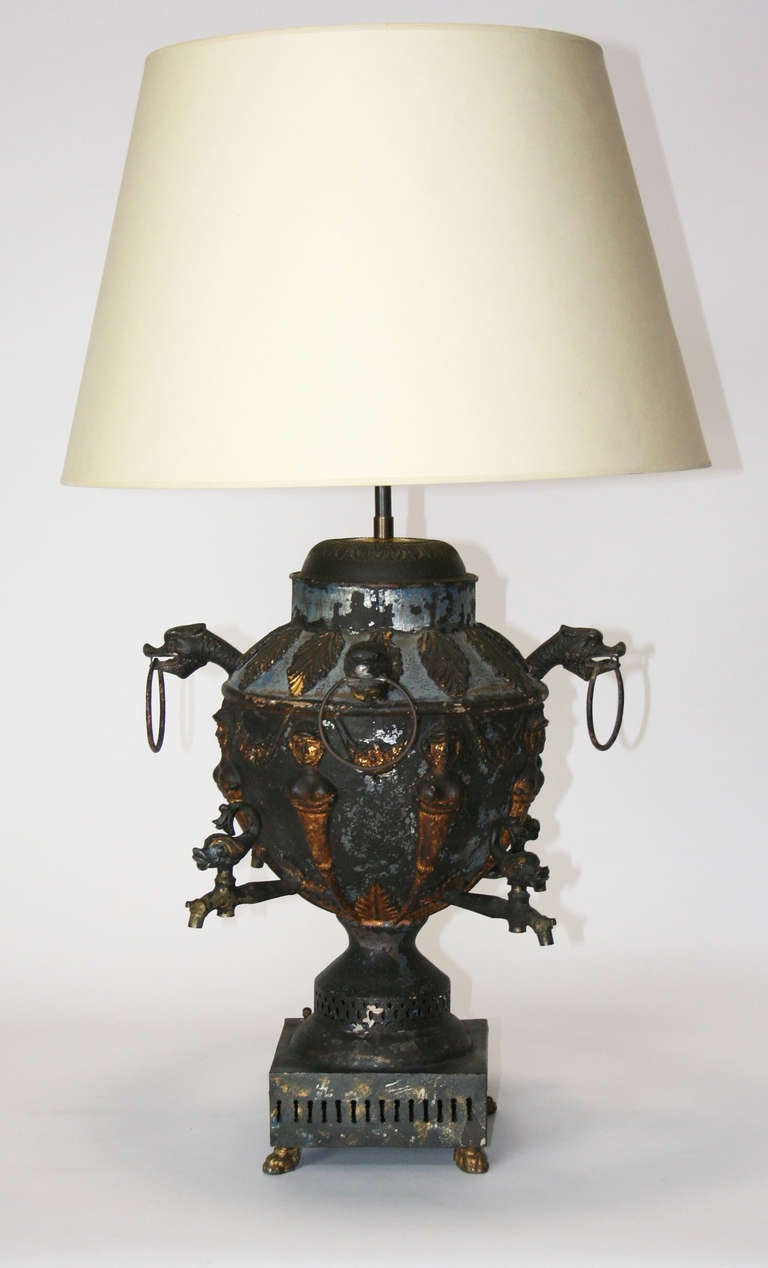 An amazing tole samovar mounted as a lamp. Wonderful patina with remnants of paint and gold leaf visible. The piece is a wonderful mixture of disparate decorative features; four dolphin handles on spouts, dragon handles, termes, and classical swags