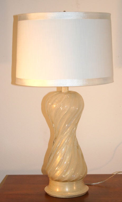 Paire de lampes glamour en verre de Murano moucheté d'or, attribuée à Barovier & Toso. La forme de sablier torsadé et cannelé est posée sur une base originale en bois peint avec des accents dorés. Hauteur jusqu'au verre supérieur 19