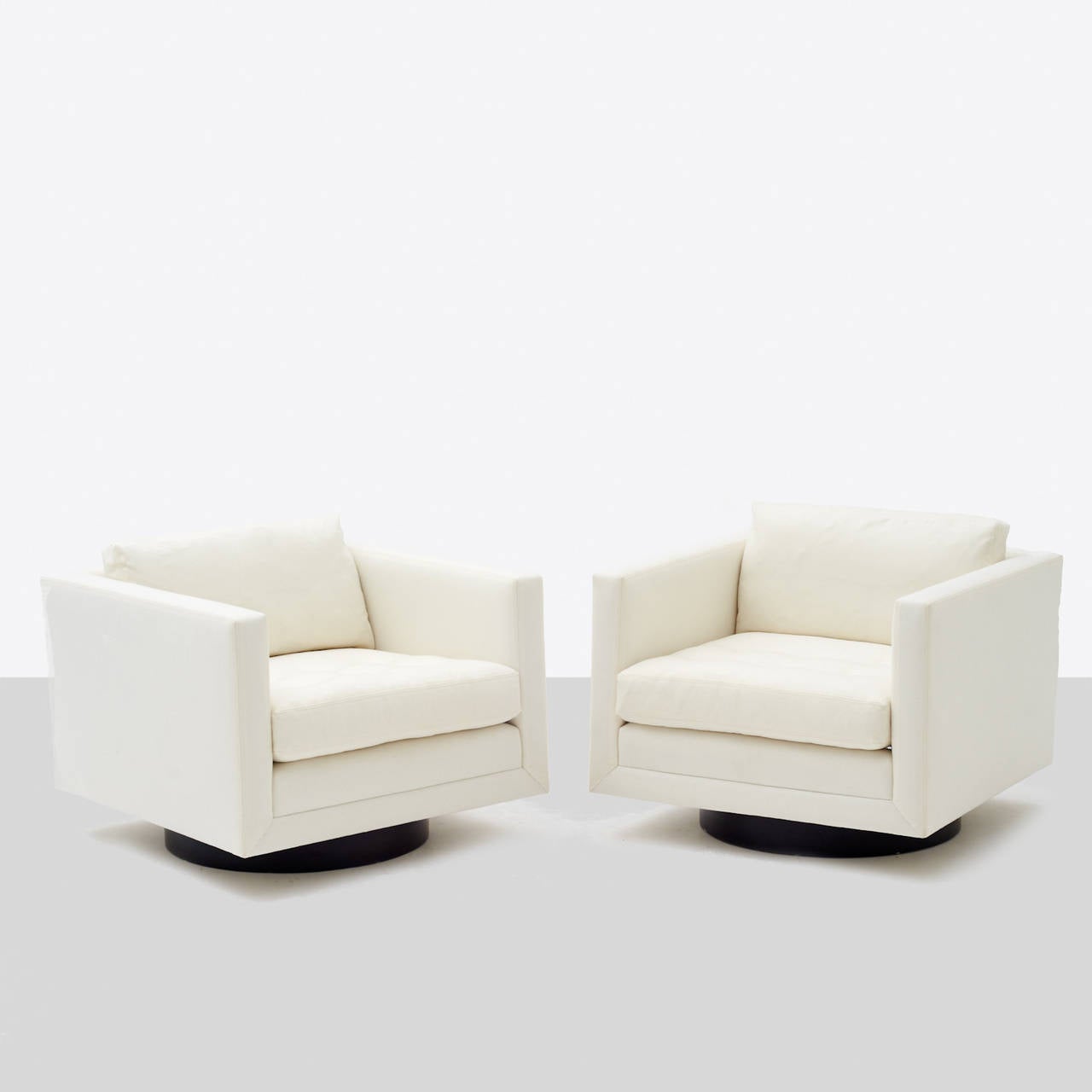 A pair of Tuxedo lounge chairs by Harvey Probber. Newly restored in a soft white wool and down cushions. Swiveling walnut base.