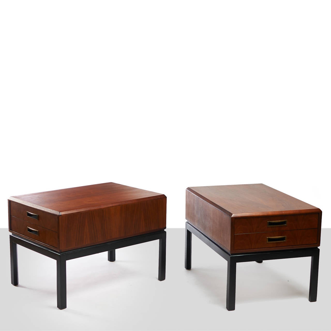 A pair of two toned walnut night stands in the style of Harvey Probber. Both feature ebonized legs, eased edges, and brass pull details on drawers.