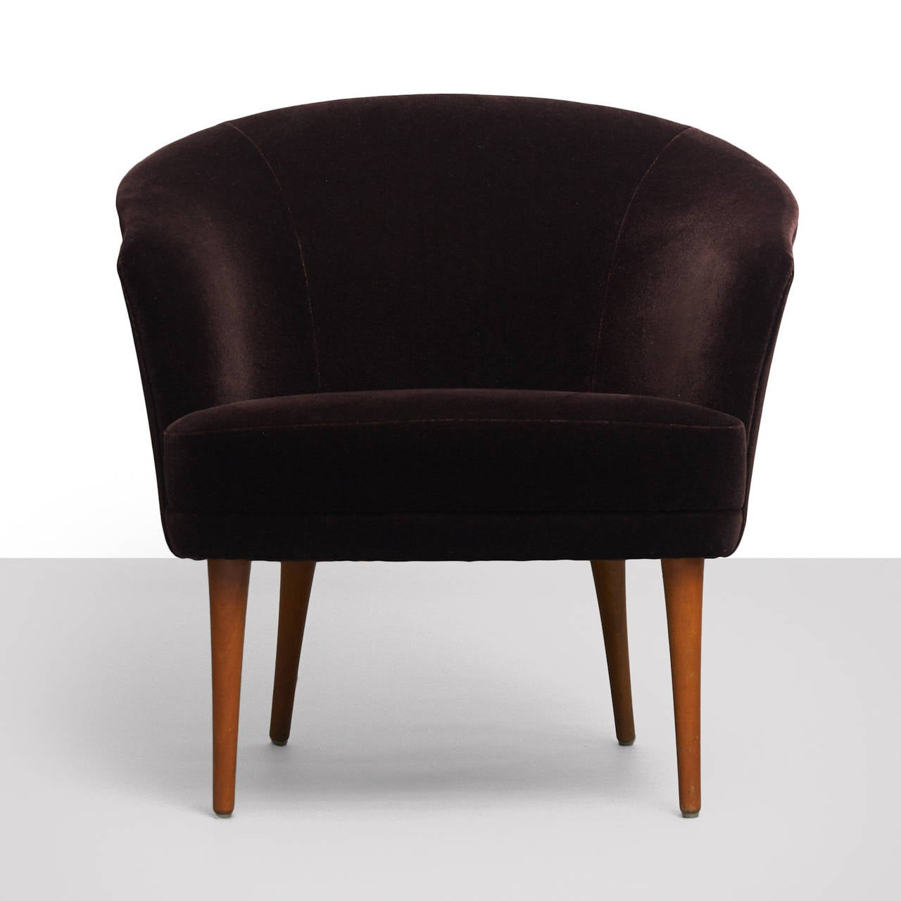 A rare lounge chair from the Triva Collection, designed by Kerstin Hörlin-Holmquist for Nordiska Kompaniet. Beautifully restored in an eggplant colored velvet upholstery, with tapered mahogany legs. Produced and labeled by Nordiska Kompaniet.