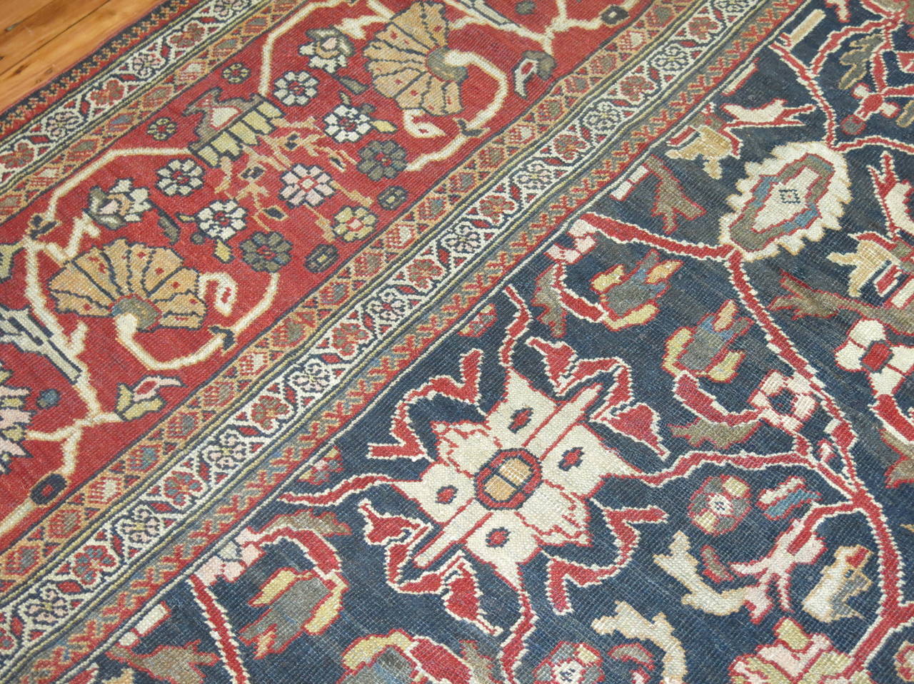 Tapis persan Sultanabad de la fin du XIXe siècle, présentant un motif masculin audacieux sur un fond bleu acier entouré d'une douce bordure rouge.