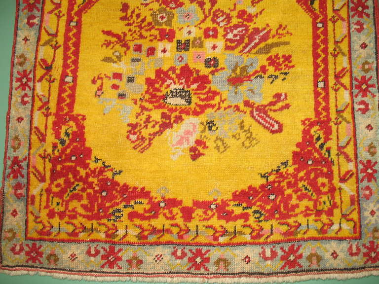 An antique Turkish Ghiordes small rug with sunshine yellow background.