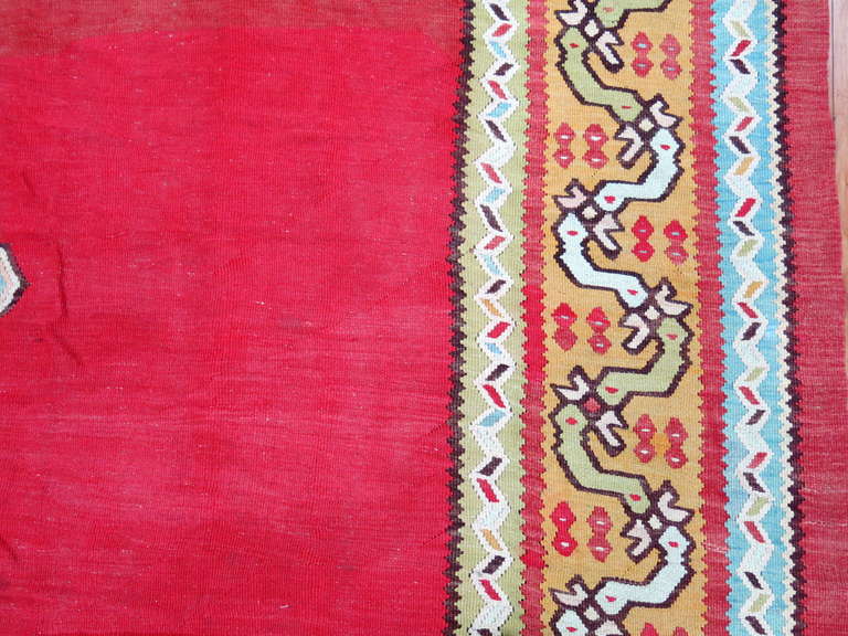 A large square Turkish Kilim in bright, rich colors.