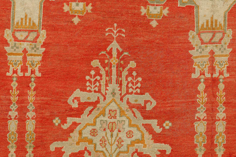 A truly divine antique Oushak masterpiece. Two identical scrolls in between an irregular set of palmettes running through coral ground with a delightful sage green and gold border. The piece is in mint condition too.