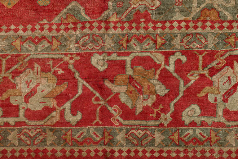 An extraordinary large square shaped antique Turkish Oushak rug. Soft green medallion and 4 corners all within a cherry red ground and matching border.