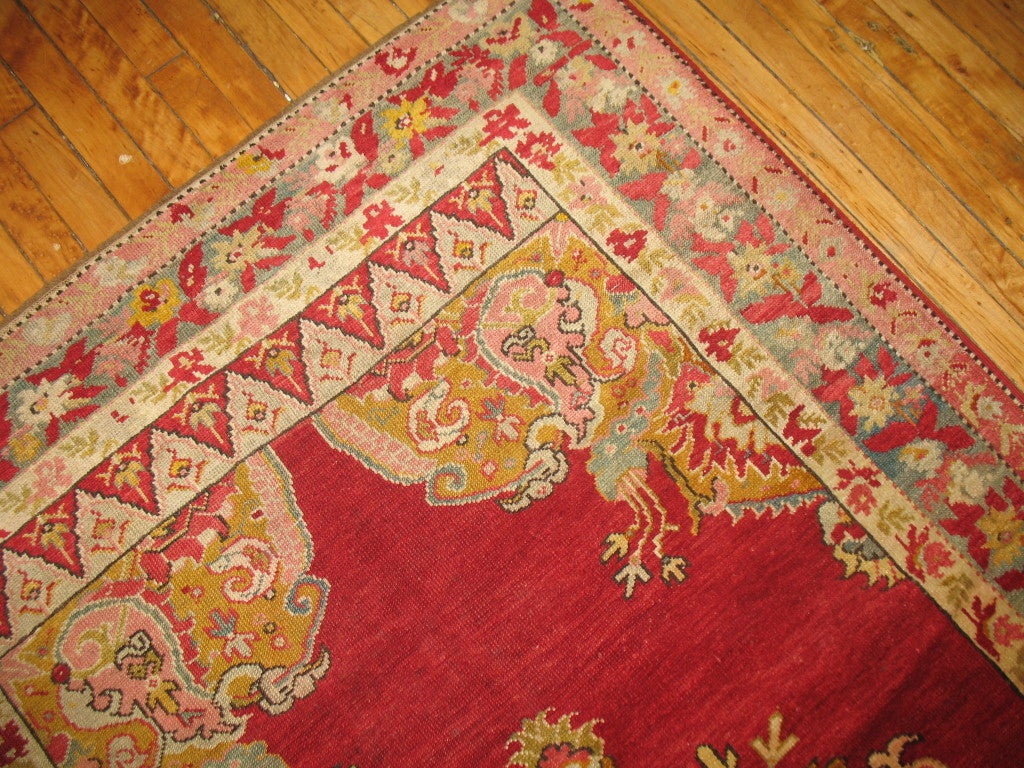 A finely woven Turkish rug executed with pristine jewel tone colors. A cherry red open field spacious motif. The floral elegantly flows with the rest of the motif. Some gold, silver and pink accents sprinkle throughout. The crafstmanship on this is