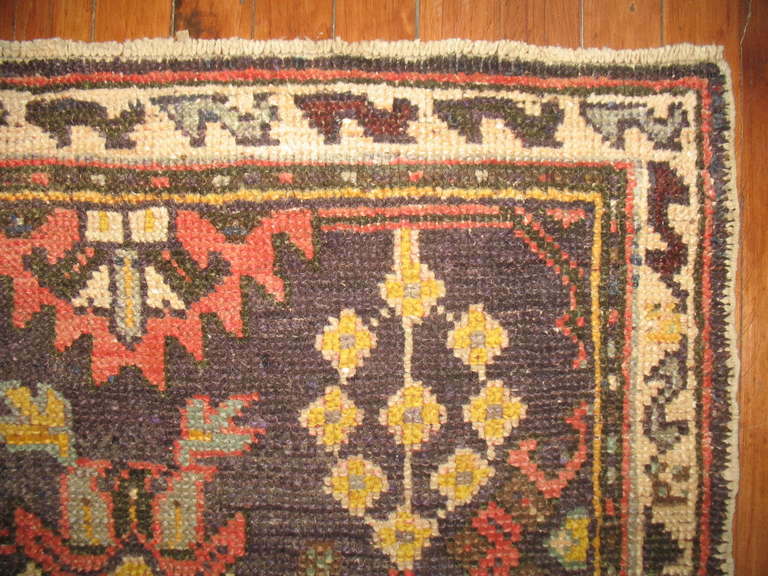 A colorful handmade antique Turkish oushak runner. A charcoal-purple colored field and coral, gray, mustard accent colors.