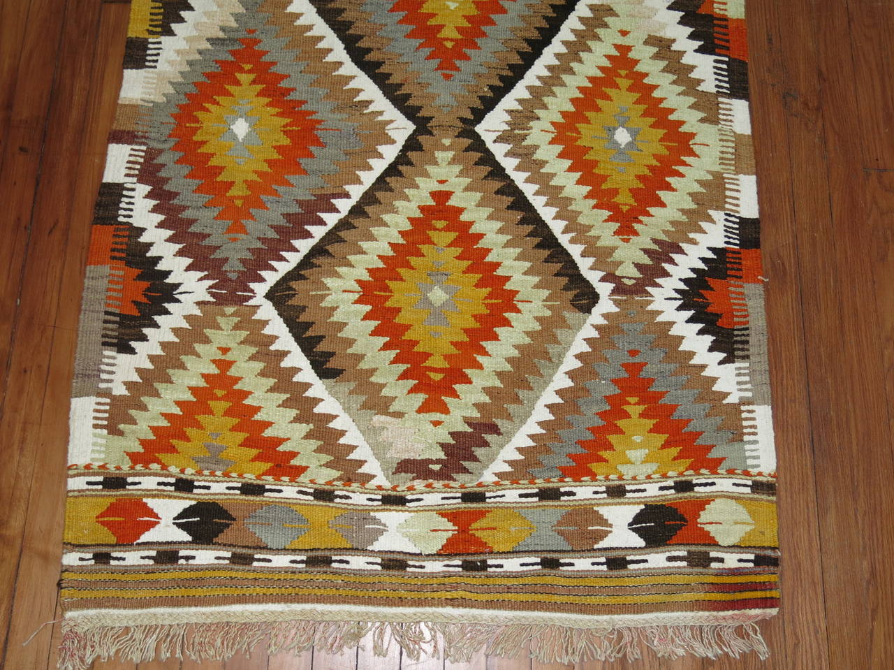 A handmade Turkish Kilim throw rug from the mid-20th century. Accents in light green, burnt orange, gray, brown

Measures: 3'3'' x 5'1''.